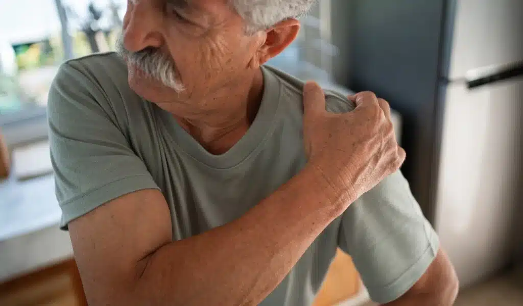 homem sentindo dor segurando o braço por causa da tendinopatia no ombro
